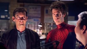 Tobey Maguire en civil est à côté d'Andrew Garfield, lui en costume de Spiderman, sauf le masque.