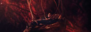 Viggo Mortensen est allongé, porté par ce qui semble être des branches d'arbres ou des veines, dans un fond indéfini, baigné dans du rouge ; scène du film Les crimes du futur.