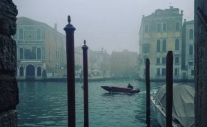 Plan d'ensemble sur Venise plongée dans la brume, un bateau passe sur la Brenta, au milieu de l'image, dans le film Veneciafrenia.