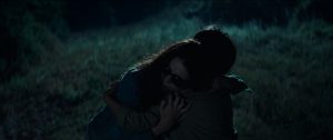 Scène de nuit dans une forêt issue du film Occhiali neri où une femme aveugle portant des lunettes de soleil noires enlace un enfant vu de dos.