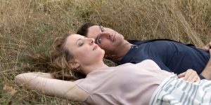 Les deux protagonistes principaux du film I'm Your Man sont allongés dans un champ, sur l'herbe ; Dan Stevens a le visage tourné vers Maren Eggert, qui elle a les yeux fermés.