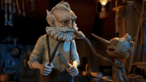 Dans l'atelier de ce dernier, Gepetto affute ses outils pendant que Pinocchio lui touche le bout du nez pour le taquiner.