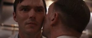 Vu de dos, un homme chuchote à l'oreille de Nicholas Hoult, qui a les larmes aux yeux ; gros plan issu du film Le Menu.