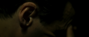 Gros plan sur l'oreille d'un homme le visage baissé, le doigt appuyé sur le front, dans le film Earwig de Lucile Hadzihalilovic.