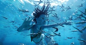 Un jeune Na'vi nage au cœur de poissons dans le film Avatar : la voie de l'eau.