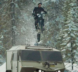 Un homme saute en moto au dessus d'un camion militaire ; plan dans des montagnes enneigées issues du film Pathaan.