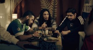 Quatre jeunes protagonistes de cité dans le film La tour de Guillaume Nicloux, échangent assis autour d'une table basse, en bazar.