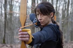 Sophie Marceau concentrée, prête à tirer à l'arc dans la forêt du film Une femme de notre temps de Jean-Paul Civeyrac.