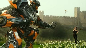 A robot géant qui lui tend une fleur, Megan Fox s'apprête à donner un coup de hache, scène issue du film Transformers de Michael Bay.