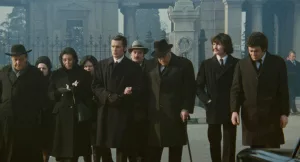 Une foule vêtue de noire quitte le cimetière après des obsèques dans le film Big Guns.