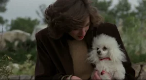Une femme apprêtée tient dans ses bras un petit caniche, dans le film de Bigas Lunas de 1979.