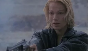Brigitte Lahaie, sous la pluie, brandit son revolver, prête à tirer, dans le film L'Exécutrice.