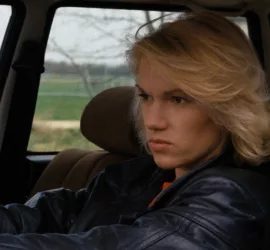 Brigitte lahaie l'air renfrogné, au volant de sa voiture dans le film L'exécutrice.