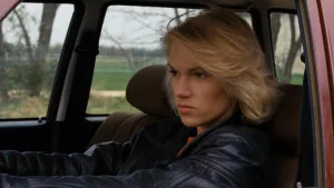 Brigitte lahaie l'air renfrogné, au volant de sa voiture dans le film L'Exécutrice.