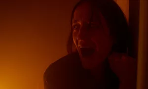 Gros plan sur le visage d'Eva Green qui hurle, en fond, un mur qui semble commencer à prendre feu, dans le film The Nocebo Effect.