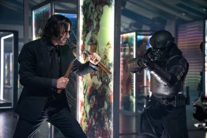 Keanu Reeves, avec un nunchaku, s'apprête à combattre contre un soldat d'assaut armé dans le film John Wick : Chapitre 4.