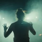 Shailene Woodley vue de dos, en contre-jour, lève les mains en l'air, sous la lumière de lampes torches qu'on devine être celles d'agent de police, dans le film Misanthrope.