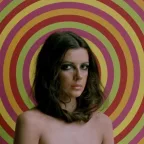 Plan rapproché-épaule sur Carole Laure face caméra, posant torse nu devant un fond de motif spirales très 70's dans La mort du bucheron de Gilles Carle.