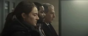 Trois agents de police en civil sont assis dans une pièce indéfinie ; leurs visages, vus de profils, sont sombres ; plan issu du film Misanthrope.