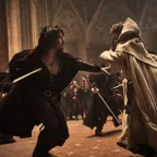 Deux mousquetaires en longue cape à capuche se battent sur le parvis d'une cathédrale dans le film Les trois mousquetaires d'Artagnan.