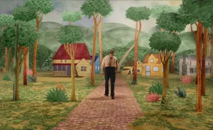 Beau (Joaquin Phoenix) vu de dos marche dans un décor en dessin, représentant de manière enfantine une vallée verte, et quelques maisons ; scène du film Beau is afraid. 