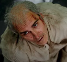 Plongée sur Joaquin Phoenix, du sang sur la tempe, qui regarde au dessus lui l'air perdu, dans le film Beau is afraid.