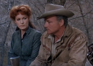 Brian Keith assis l'air pensif et triste, son chapeau de cow-boy vissé sur la tête ; à ses côtés, Maureen O'Hara le scrute avec attention ; scène du film New Mexico pour le livre Le cinéma de Sam Peckinpah.