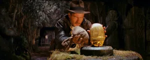 Indiana Jones dans une grotte s'apprête à dérober une pierre dorée.