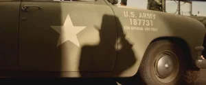 L'ombre d'Indiana Jones prenant une photo se projette sur une jeep de la US Army.