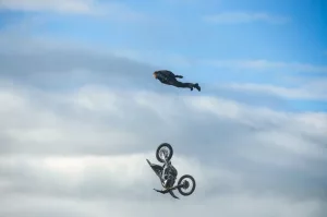 Tom Cruise dans les airs, plane au dessus d'une moto en pleine chute.