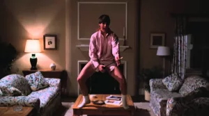 Tom Cruise en pyjama joue de la air guitar dans le salon du film Risky Business.