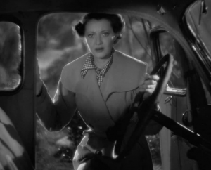 Sylvia Signal vue de face, le visage pétri d'inquiétude, ouvrant la porte côté conducteur d'une automobile et s'accrochant au volant avec sa main gauche, dans le film J'ai le droit de vivre.