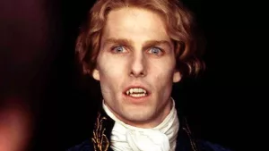 Plan rapproché-épaule sur Tom Cruise en vampire blond, l'air fasciné, et canines visibles, dans le film Entretien avec un vampire.