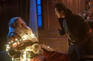 John Leguizamo séquestre le Père Noël, ligoté avec des guirlandes allumées dans le film Violent Night.