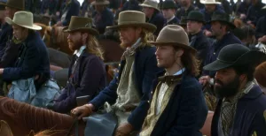 Une foule d'hommes à cheval, tous tournés vers la même direction, comme s'ils attendaient, en tenue de ville et chapeau, dans le film Chevauchée avec le diable.