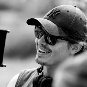 Portrait de Bastien Milheau souriant, sur un tournage, en noir et blanc.