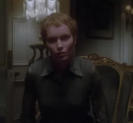 Plan rapproché-taille, issu du film Le cercle infernal, sur Mia Farrow, assise sur un vieux fauteuil dans un fauteuil sombre, qui observe en notre direction avec un regard fantomatique.