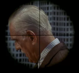 Vu à travers la lunette du sniper, un vieil homme vu de profil, la tête baissée, dans le film La cible.