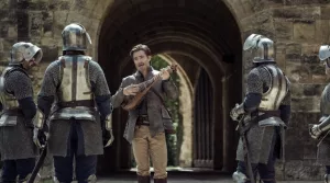 Lé héros du film Donjons & Dragons : l’honneur des voleurs joue le barde devant quatre chevaliers, vus de dos.
