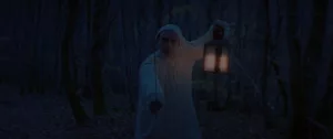 Un homme en pyjama blanc avance dans la forêt, une épée dans la main, et une lampe à huile de l'autre ; scène de nuit dans Le vourdalak d'Adrien Beau.