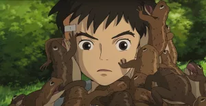 De multiples crapauds marrons grimpent sur le visage de Mahito dans le film Le garçon et le héron.