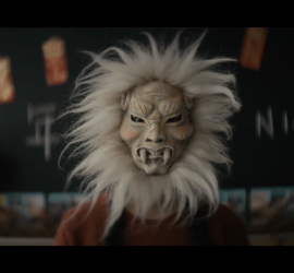 Plan rapproché-épaule sur une jeune fille portant un masque tribal asiatique faisant penser à un lion dans le film Nian pour notre carnet de bord Court-Métrange 2.