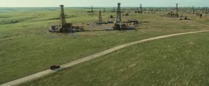 Plan d'ensemble sur des foreuses à pétrole sur une vaste étendue d'herbe, issu du film Killers of the flower moon.