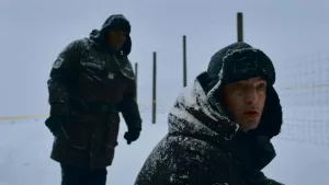 Deux hommes en pleine neige, chapka et doudoune, ont l'air interdit et étonnés face à une clôture, dans la série Polar park.