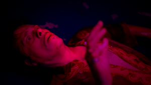 L'acteur Karim Barras allongé sous une lumière rose fluo, les mains en l'air, effrayé, dans le film The Belgian Wave.