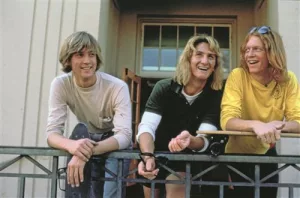Trois beaux gosses blonds aux cheveux longs s'esclaffent sur une terrasse dans le film Ça chauffe au lycée Ridgemont.