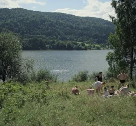 Une famille se prélasse sur l'herbe au bord d'un lac, au cœur d'une vallée verte et ensoleillée, dans le film The Zone of Interest.