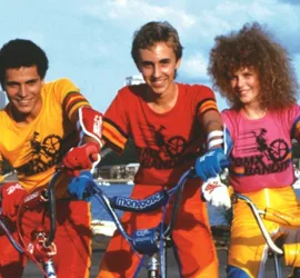 Les trois bikers en tenue fluo du film BMX Bandits posent fièrement, tout souriants, devant un port.