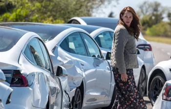 Julia Roberts scrute une rangée de voitures de sport blanches, toutes du même modèle, garées en bordure de campagne, dans le film Le monde après nous.