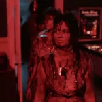 Deux jeunes adolescentes avancent dans un bar plongé dans une lumière rouge ; elles sont ensanglantées, et leur regard est hagard ; plan issu du film Réveillon sanglant.